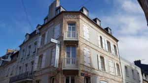 a tall brick building with a street sign on it at Hotel Le Trouville in Trouville-sur-Mer