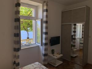 sypialnia z dużym oknem i telewizorem w obiekcie Apartments Kirigin w Dubrowniku