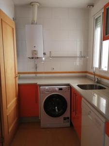 uma cozinha com uma máquina de lavar roupa e um lavatório em WISH SUITE MORERA em Sevilha