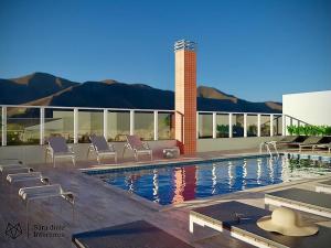 einen Pool mit Stühlen neben einem Gebäude in der Unterkunft SOLAMAR - PRAIA Das TONINHAS in Ubatuba