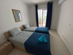 a bedroom with two beds and a couch and a window at Sunshine Apartments Mellieha - modern three bedroom ground floor apartment with yard in Mellieħa