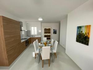 ein Esszimmer mit einem Tisch und weißen Stühlen in der Unterkunft Sunshine Apartments Mellieha - modern three bedroom ground floor apartment with yard in Mellieħa