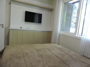 1 dormitorio con 1 cama y TV de pantalla plana en la pared en Apartamento Lindo Central, en Gramado