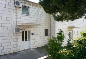 a white brick building with a white door at Apartment & Room Braica in Dubrovnik