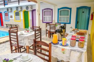 un restaurant avec des tables et des chaises avec de la nourriture dessus dans l'établissement Pousada Primavera, à Parati