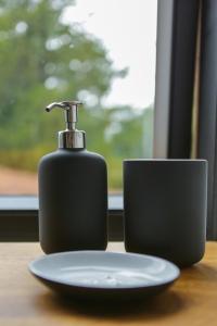 a soap dispenser on a table next to a plate at Amand'eau - zwemvijver, zonneterras, grote tuin in Sint-Amands