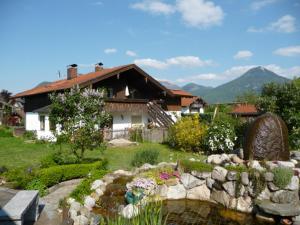 a house with a pond in front of a garden at Mondscheinwinkl in Flintsbach