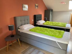 2 Betten in einem Zimmer mit orangefarbener Wand in der Unterkunft Ferienhäuser Schlossberg in Zandt