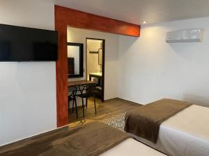 ein Hotelzimmer mit einem Bett und einem Flachbildfernseher in der Unterkunft Hotel Raices de Mar in Mazatlán