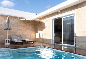 a swimming pool with two chairs and an umbrella at Villa Eris in Puerto del Carmen