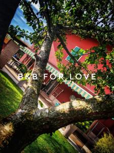 uma árvore em frente a um edifício vermelho com o saco de palavras para o amor em B&B Il Tramonto em Pastrengo