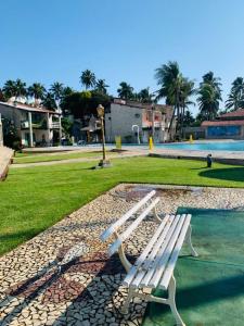 a white bench sitting in a park next to a pool at Flats Privé Village Galés in Maragogi