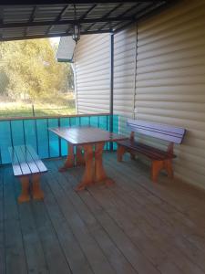 two benches and a picnic table on a deck at Уютный домик в деревне in Privolzhsk