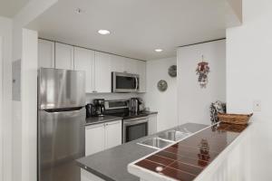 a kitchen with white cabinets and a stainless steel refrigerator at Tyndall stone lodge by Cozystay signature Whistler in Whistler