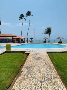 a large swimming pool next to a beach with the ocean at Flats Privé Village Galés in Maragogi