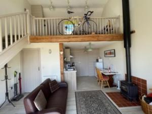 a living room with a couch and a bike on a loft at Bike Shed - Beautiful 1-Bed Cottage in Shorwell in Shorwell