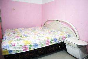 a small bed in a room with pink walls at Charisma Residence Syariah in Surabaya