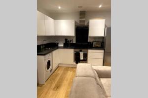 a kitchen with white cabinets and a couch at Luxury 1 Bedroom Apartment with Netflix & Parking in Borehamwood