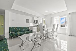 a white living room with a green couch and a table at Hotel Belleza in Miami Beach