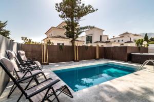 a backyard with a swimming pool and two chairs at THE JUNGLE VILLA - 4BDR Private Pool/Jacuzzi/BBQ in Benalmádena