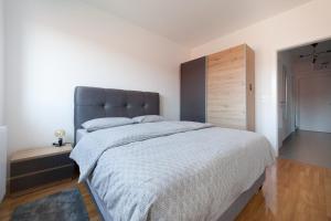 a bedroom with a large bed with a gray headboard at Apartman Pepper in Osijek