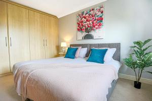 a bedroom with a large white bed with blue pillows at Executive Monkston Apartment by PAY AS U STAY in Milton Keynes