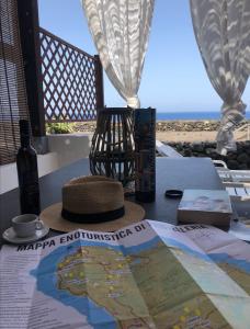 un cappello seduto su un tavolo con una mappa e un libro di Perla Nera I DAMMUSI DI SCAURI a Pantelleria