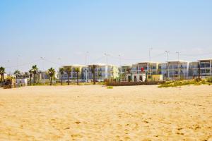 a sandy beach with buildings in the background at CASABAY Sidi Rahal, appartement avec accés direct à la plage et piscine in Sidi Rahal