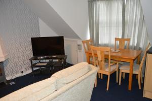 a living room with a couch and a table with a television at Holiday Apartment Dunfermline in Dunfermline