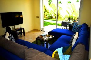 a living room with blue couches and a tv at CASABAY Sidi Rahal, appartement avec accés direct à la plage et piscine in Sidi Rahal