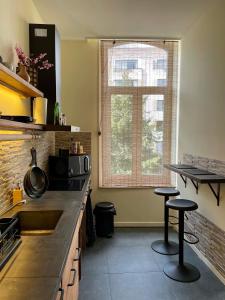 a kitchen with a counter and two stools at SLEEP INN - Japanese Loft with balconyview citycenter in Antwerp