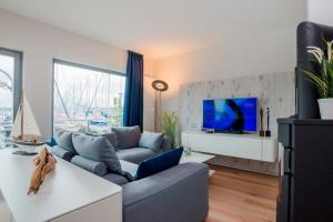 ein Wohnzimmer mit einem Sofa und einem TV in der Unterkunft Ostsee - Maisonette - Appartement Nr 54 "Marina-Blick" im Strand Resort in Heiligenhafen