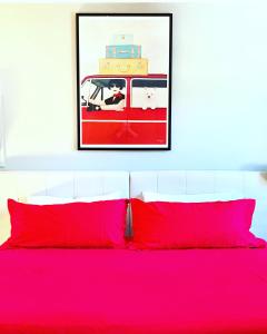 a bed with red pillows and a picture on the wall at Remington Flats in Fort Collins