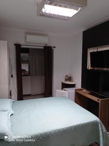 um quarto com uma cama e uma televisão de ecrã plano em Eilat. אילת Pousada Bacacheri em Curitiba