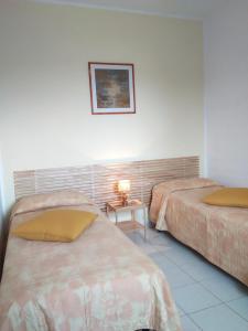 a bedroom with two beds and a table with a lamp at Casa Barbara - servizi inclusi - services included in Capoliveri