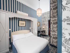 a room with a bed, a desk, and a painting on the wall at Hôtel Saint Germain in Paris