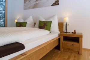 een slaapkamer met een wit bed met groene kussens bij Steinbock Superior Appartement in Zell am See