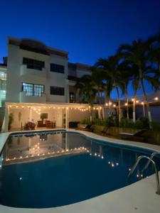 a swimming pool in front of a house at night at Hotel Balxibá alberca y estacionamiento in Playa del Carmen