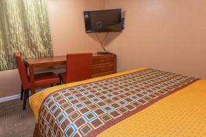 a hotel room with a bed and a desk and a television at Far West Motel in Forks