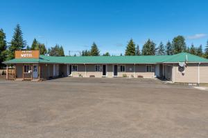 a building with a green roof and a parking lot at Far West Motel in Forks