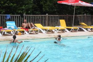 a man and two children playing in a swimming pool at Village de Gite - La Cascade in Sainte-Eulalie-dʼOlt
