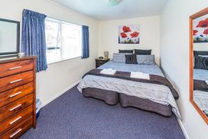 1 dormitorio con cama, tocador y espejo en Anndion Lodge Motel & Conference Centre, en Whanganui