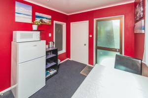 Habitación roja con nevera y microondas. en Anndion Lodge Motel & Conference Centre, en Whanganui