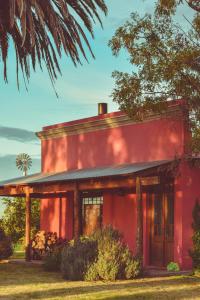 ein rotes Haus mit einem Baum davor in der Unterkunft Casa de Campo La Colorada in Las Flores