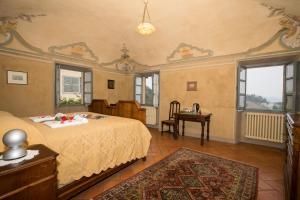 um quarto com uma cama, uma mesa e janelas em Palazzo Tornielli em Mombello Monferrato