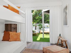 a bedroom with a white bed and a large window at The Bach in Byron in Byron Bay