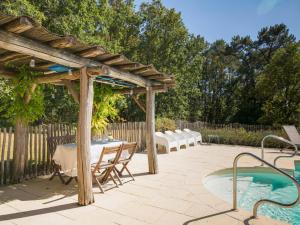 eine Terrasse mit einem Tisch, einer Pergola und einem Pool in der Unterkunft La petit Gapard in Issac