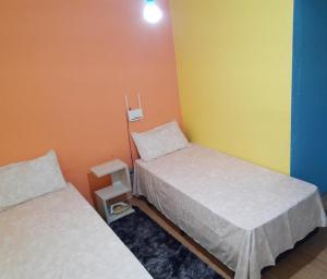 Habitación con 2 camas y pared amarilla y naranja. en Sobrado Livramento Rivera Diaria, en Santana do Livramento