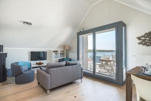 ein Wohnzimmer mit einem Sofa und einer Glasschiebetür in der Unterkunft Ostsee - Appartement Nr 20 "Oberdeck" im Strand Resort in Heiligenhafen