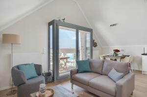a living room with a couch and a glass door at Ostsee - Appartement Nr 20 "Oberdeck" im Strand Resort in Heiligenhafen